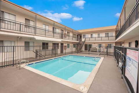 A swimming pool is surrounded by a black fence in a courtyard.