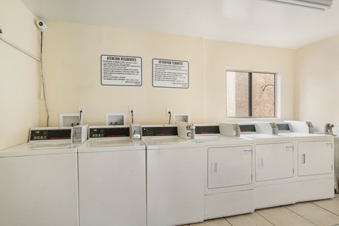 A row of washing machines are in a laundromat.