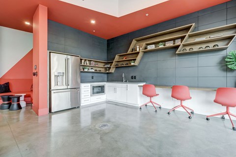A kitchen with a red accent wall and a white counter.