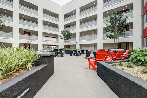 A courtyard with red chairs and a black bench.