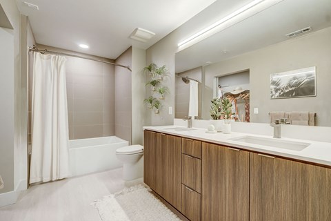 A modern bathroom with a white tub and wooden cabinets.