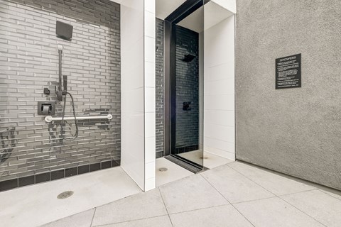 A bathroom with a glass shower door and a white tile wall.