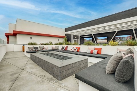 A modern outdoor seating area with a fire pit and cushions.