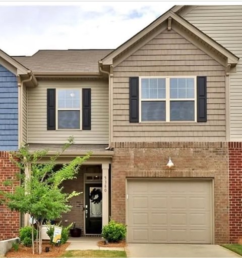 A house with a grey garage door and a brick wall.