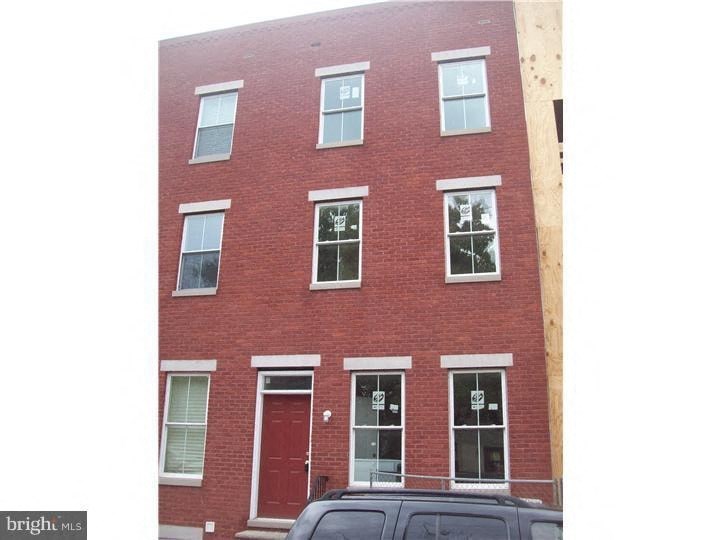 A red brick building with a black car parked in front.