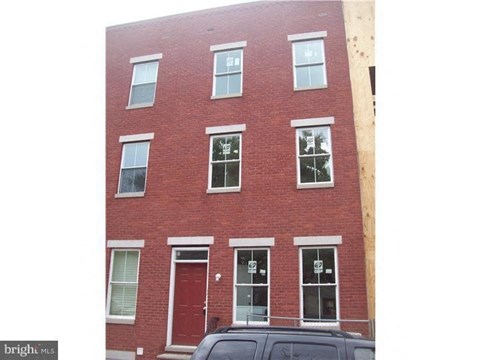 A red brick building with a black car parked in front.