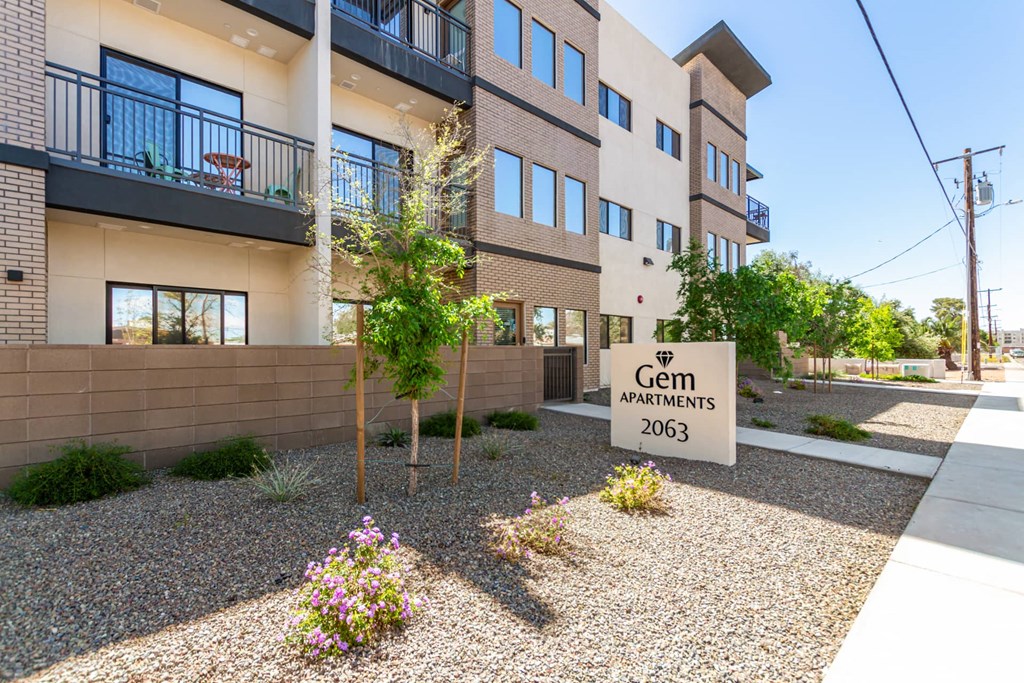 A building with the sign "Gem Apartments 2063" in front of it.