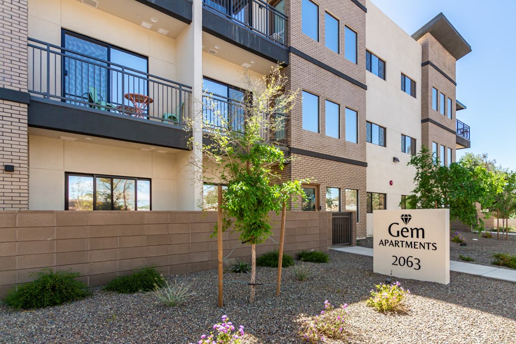 A building with a sign that says Gem Apartments 2063.