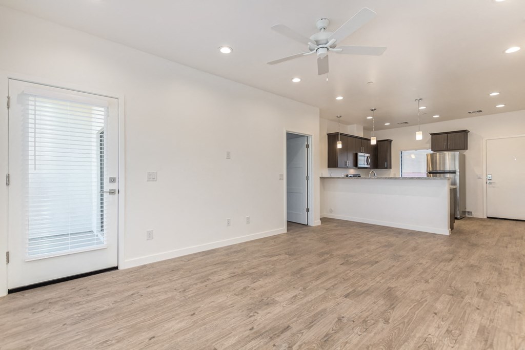 A spacious room with a ceiling fan and a kitchen area in the background.