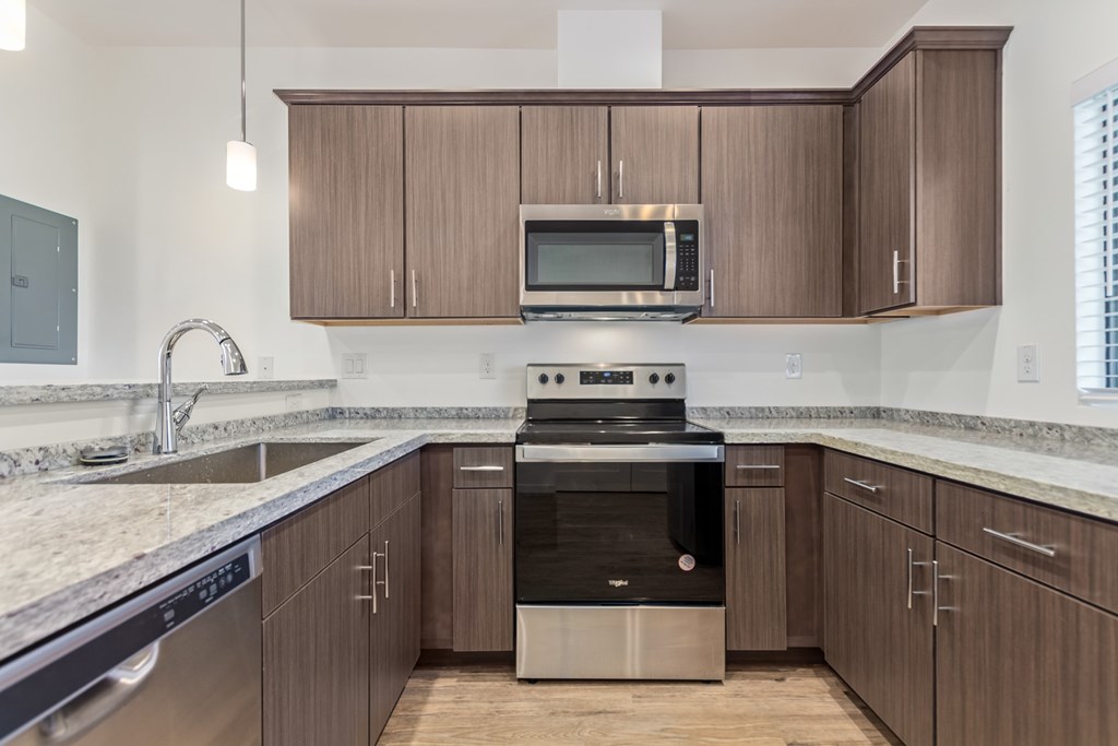 A modern kitchen with dark wood cabinets and stainless steel appliances.