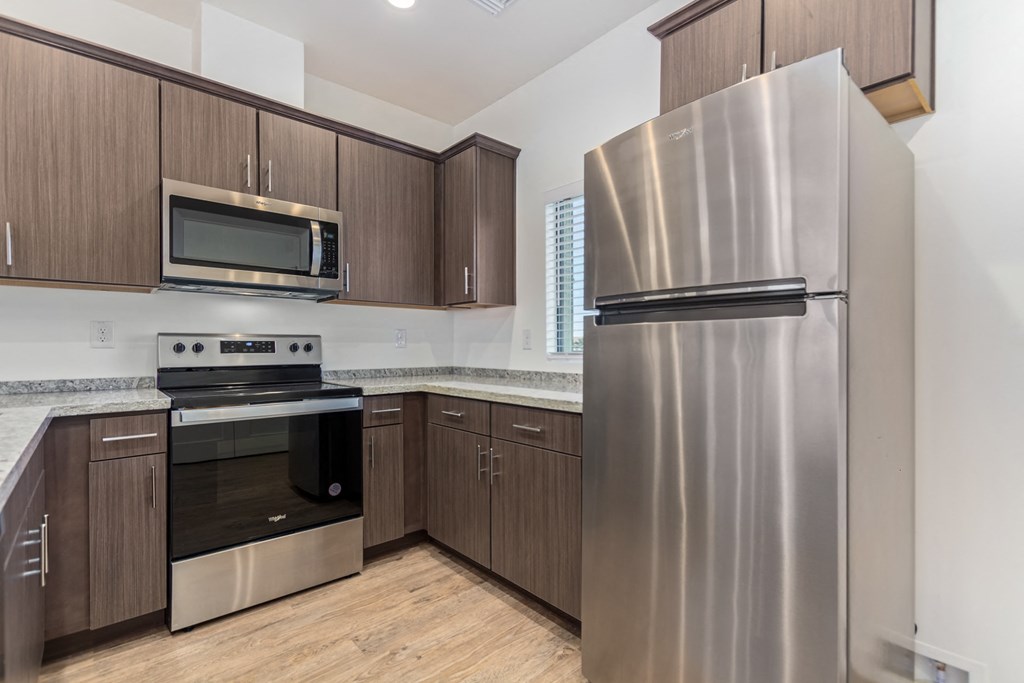 A kitchen with a stainless steel refrigerator, microwave, and oven.