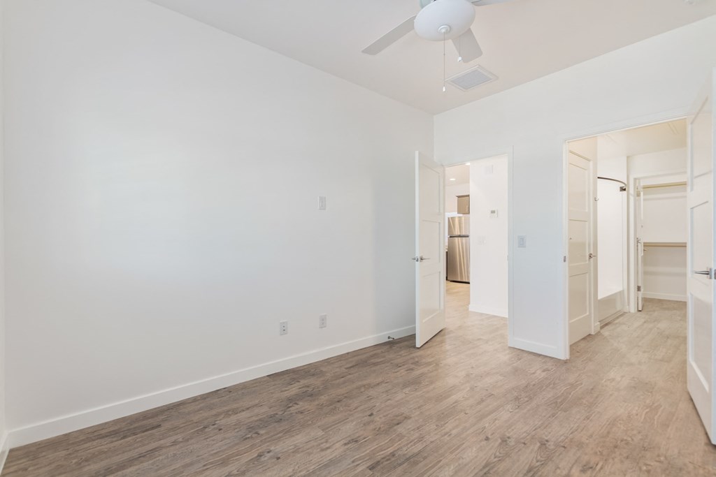 A room with a ceiling fan and wooden flooring.