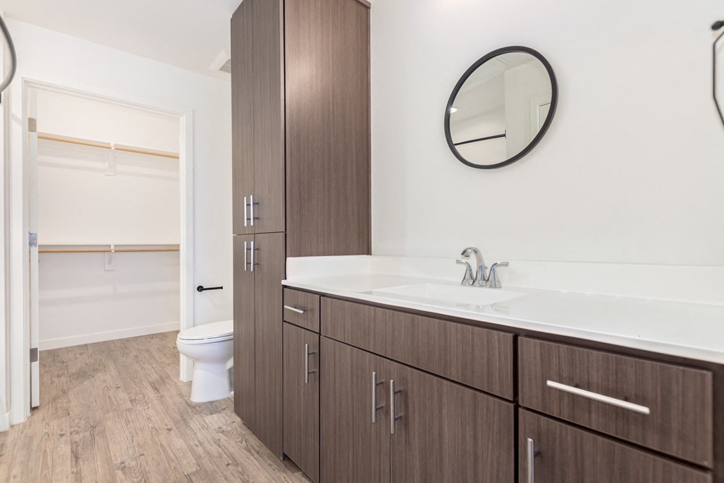 A bathroom with a toilet, sink, and wooden cabinets.