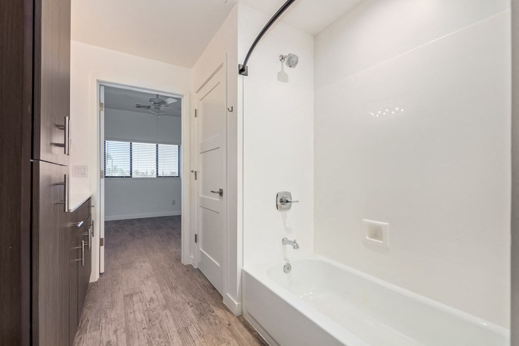 A white bathroom with a tub and a window.
