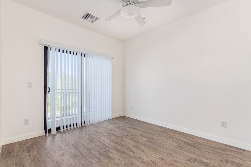 A room with a sliding glass door and a ceiling fan.