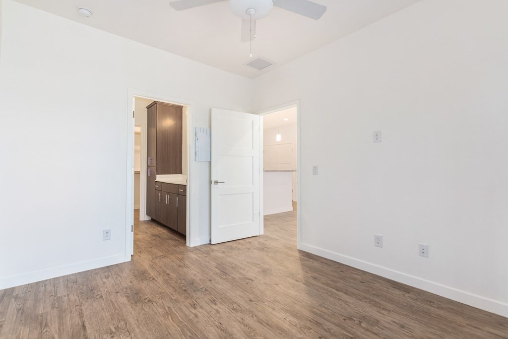 A room with a ceiling fan and a doorway leading to a kitchen.