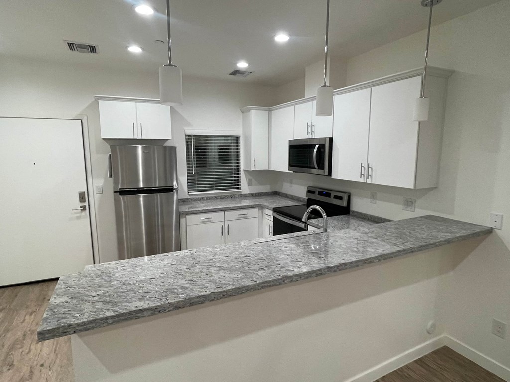 A modern kitchen with white cabinets and stainless steel appliances.