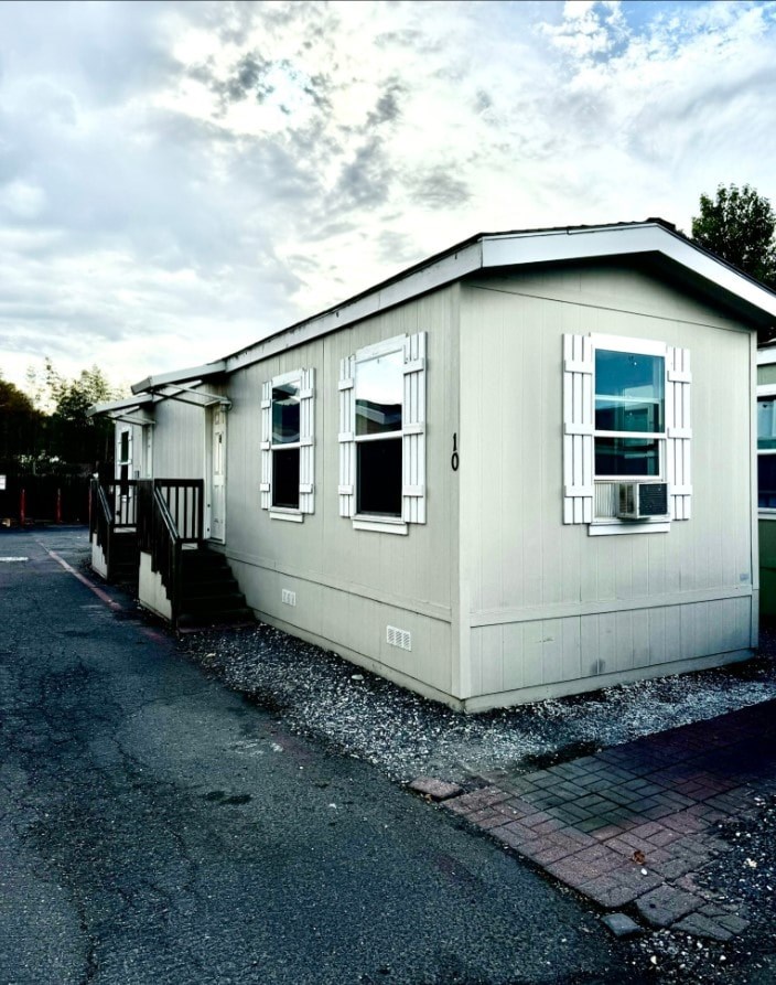 A small white building with a black roof and a black gate.