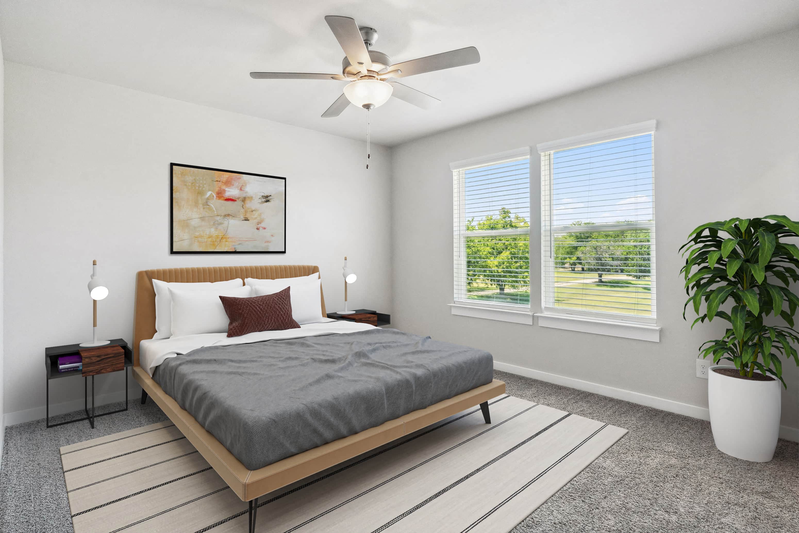 A bedroom with a bed, a ceiling fan, and a potted plant.
