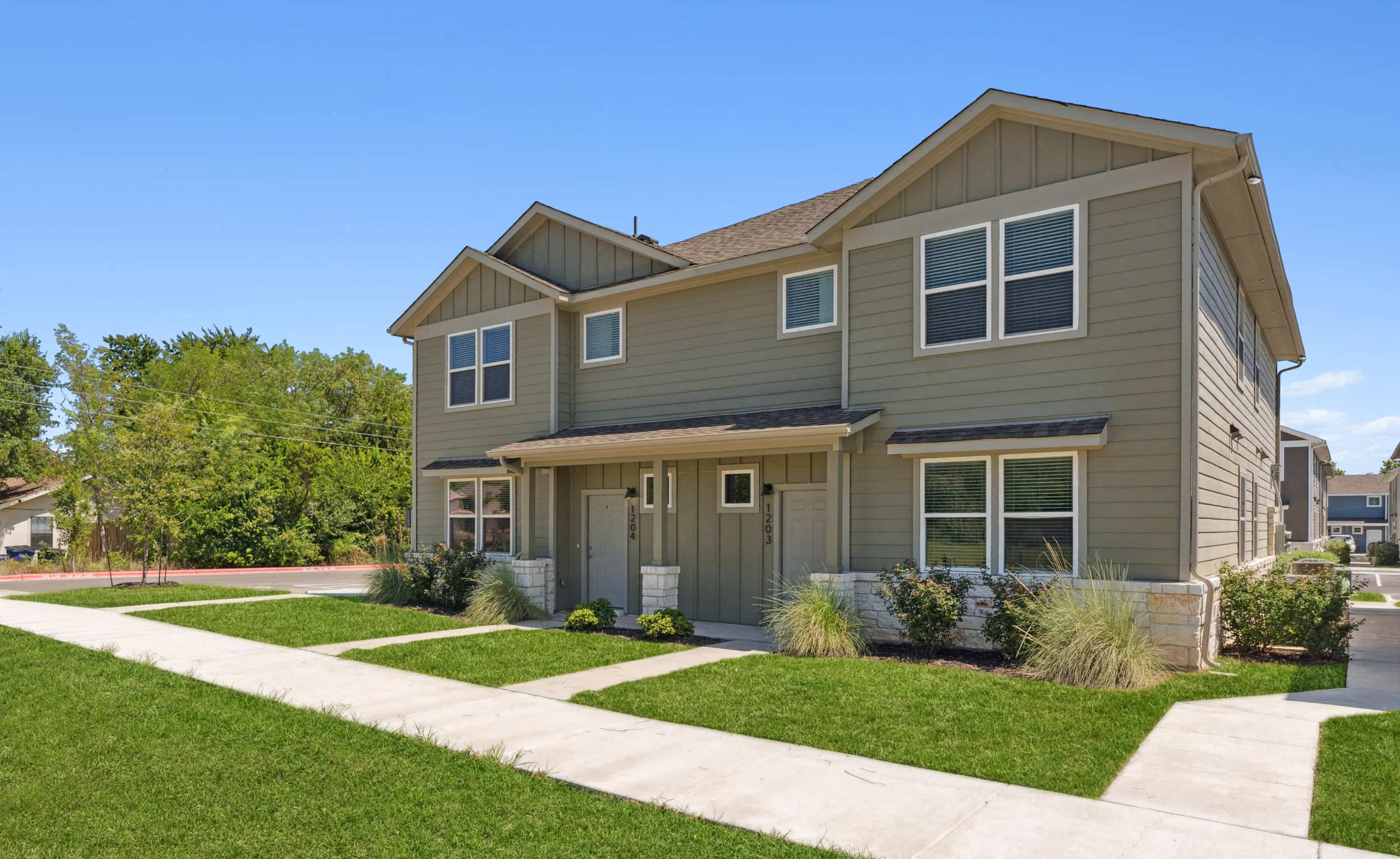 A two-story house with a gray siding exterior and a brown roof.