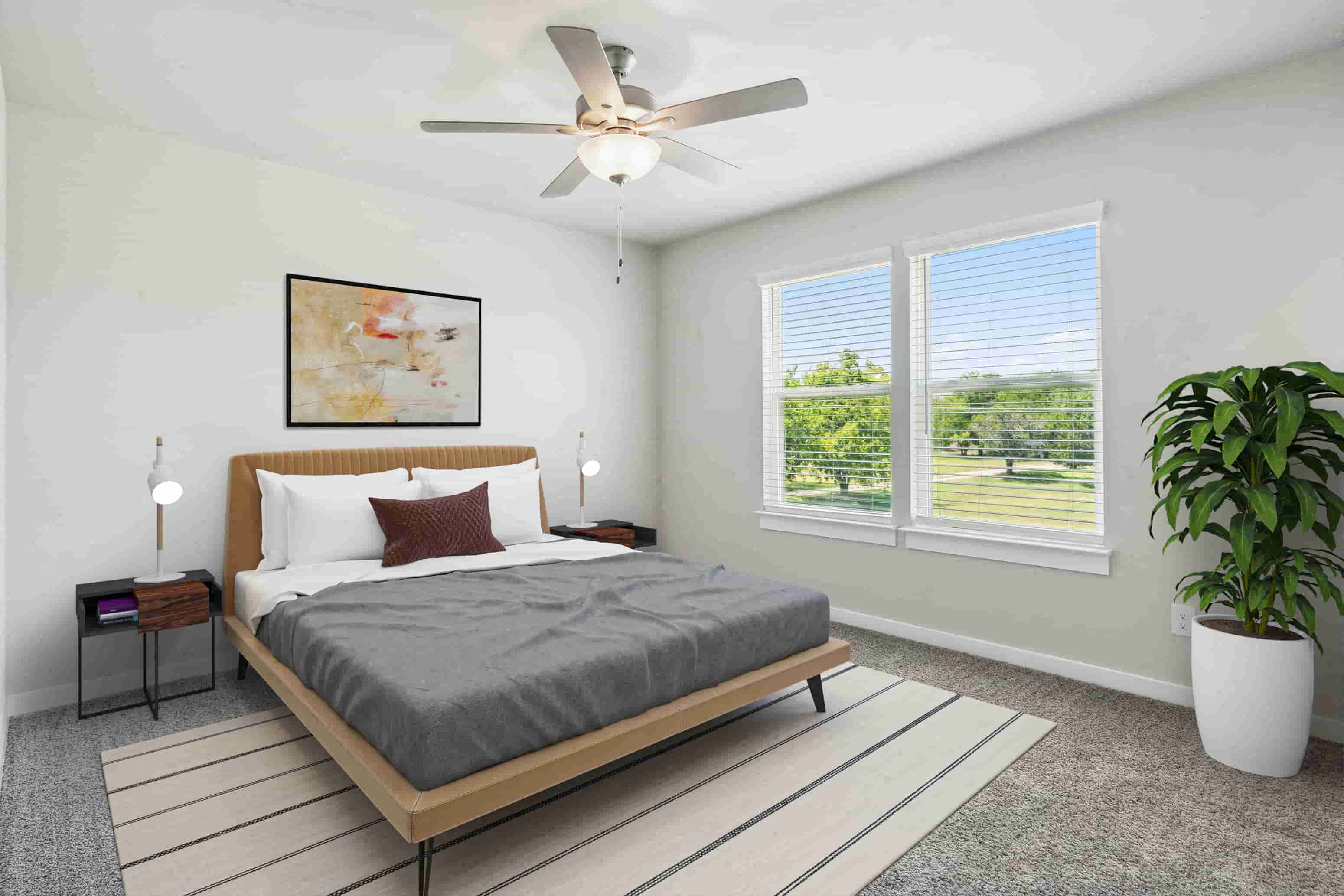A bedroom with a large bed, a ceiling fan, and a view of the outdoors through the window.