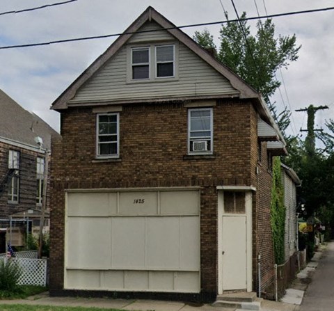 A two-story brick house with a garage door that says 1925 on it.