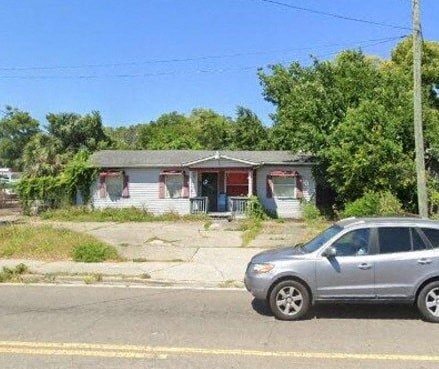 A silver car is parked on the side of a road in front of a house.