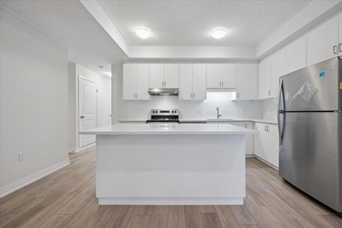 A white kitchen with a refrigerator on the right.