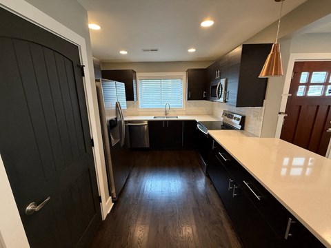 A modern kitchen with black cabinets and a white countertop.
