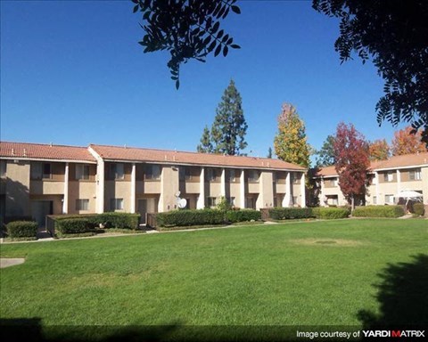 an apartment building with a green lawn in front of it