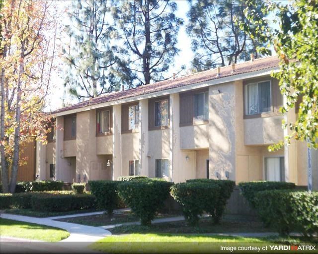 an apartment building with bushes and trees in front of it
