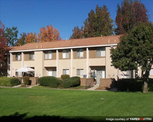a large apartment building with a lawn and trees