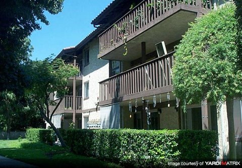 A building with a balcony and a hedge in front.