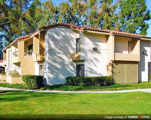 A two-story house with a red tile roof and a balcony on the second floor.