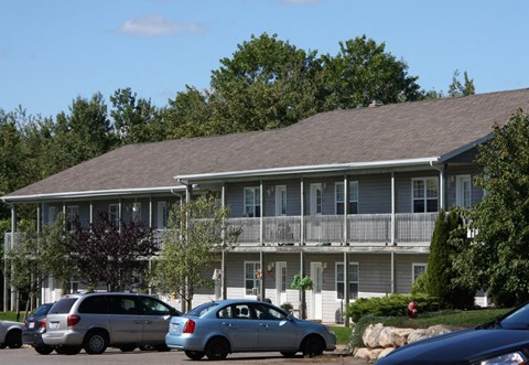 A silver minivan is parked in front of a two-story house.
