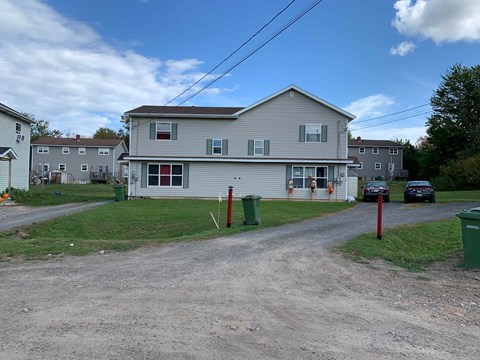 A house with a grey roof and a red door is surrounded by other houses.
