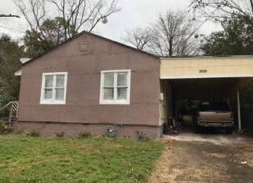 A brown house with a white window and a car in the garage.