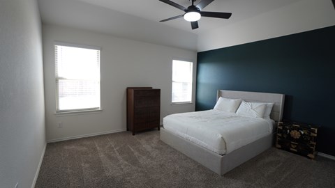 A bedroom with a bed, dresser, and ceiling fan.