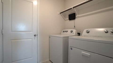 A white door is on the left of a small laundry room.