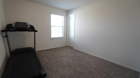 A room with a treadmill and a window.