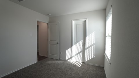 A room with a carpeted floor and a door on the left side.