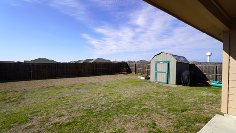 A backyard with a fence and a shed.