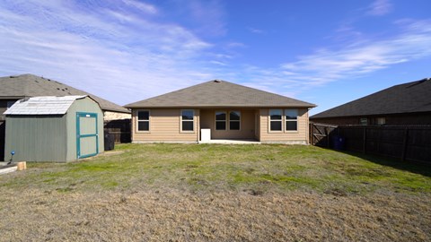 A house with a brown roof and a green door is surrounded by a fence.