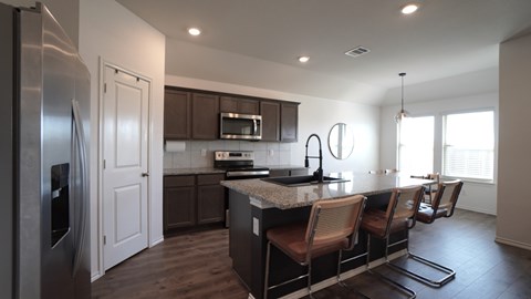 A modern kitchen with dark wood cabinets and a stainless steel refrigerator.