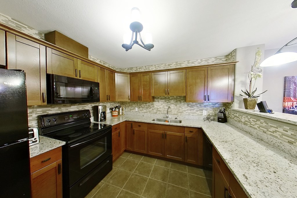 A kitchen with black appliances and wooden cabinets.