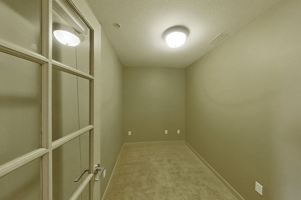A hallway with a door on the left and two lights on the ceiling.
