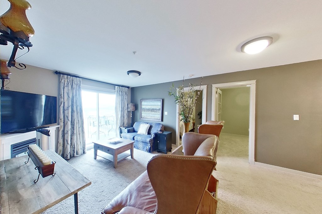 A living room with a couch, a chair, a coffee table, and a television.
