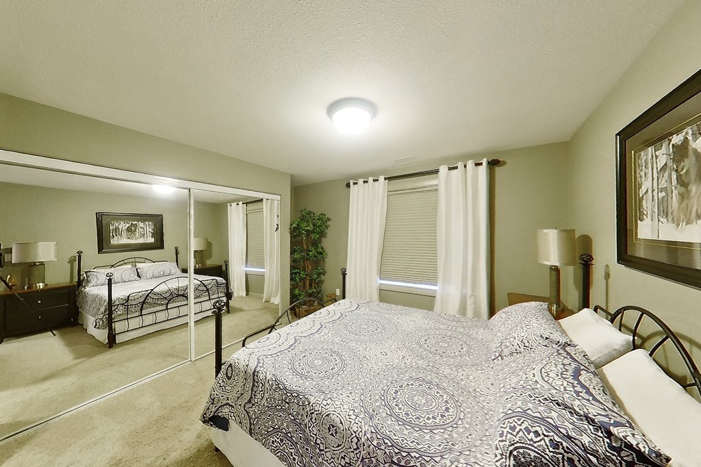 A bedroom with a large bed and a mirror on the wall.