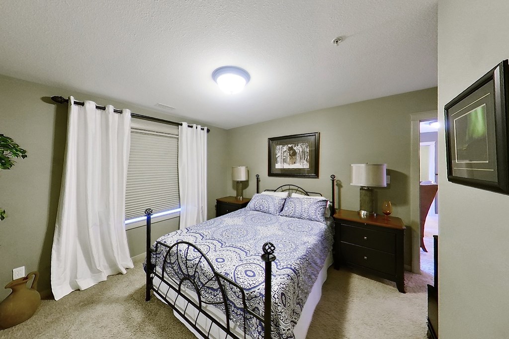 A bedroom with a bed, nightstands, and a window with curtains.