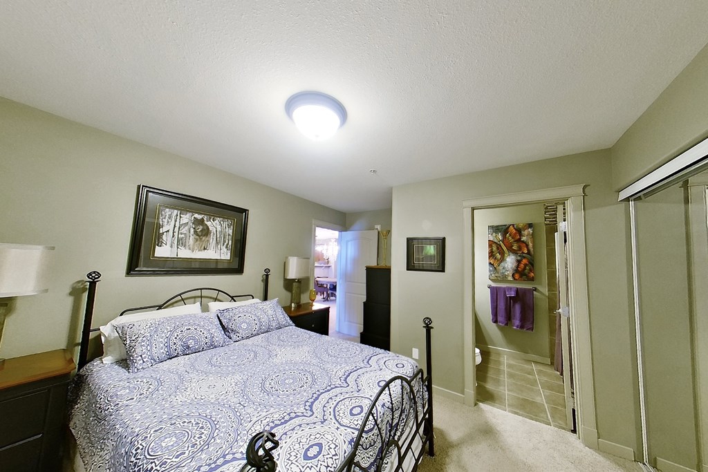 A bedroom with a bed, nightstand, and lamp.